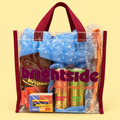 A Brightside clear plastic tote bag with maroon handles and trim, filled with assorted merch including blue packing material, a cap, 2 brightside sodas, a small camera, and a koozie, set against a pale yellow background. The bag has a large 'on the brightside' logo printed on the front.