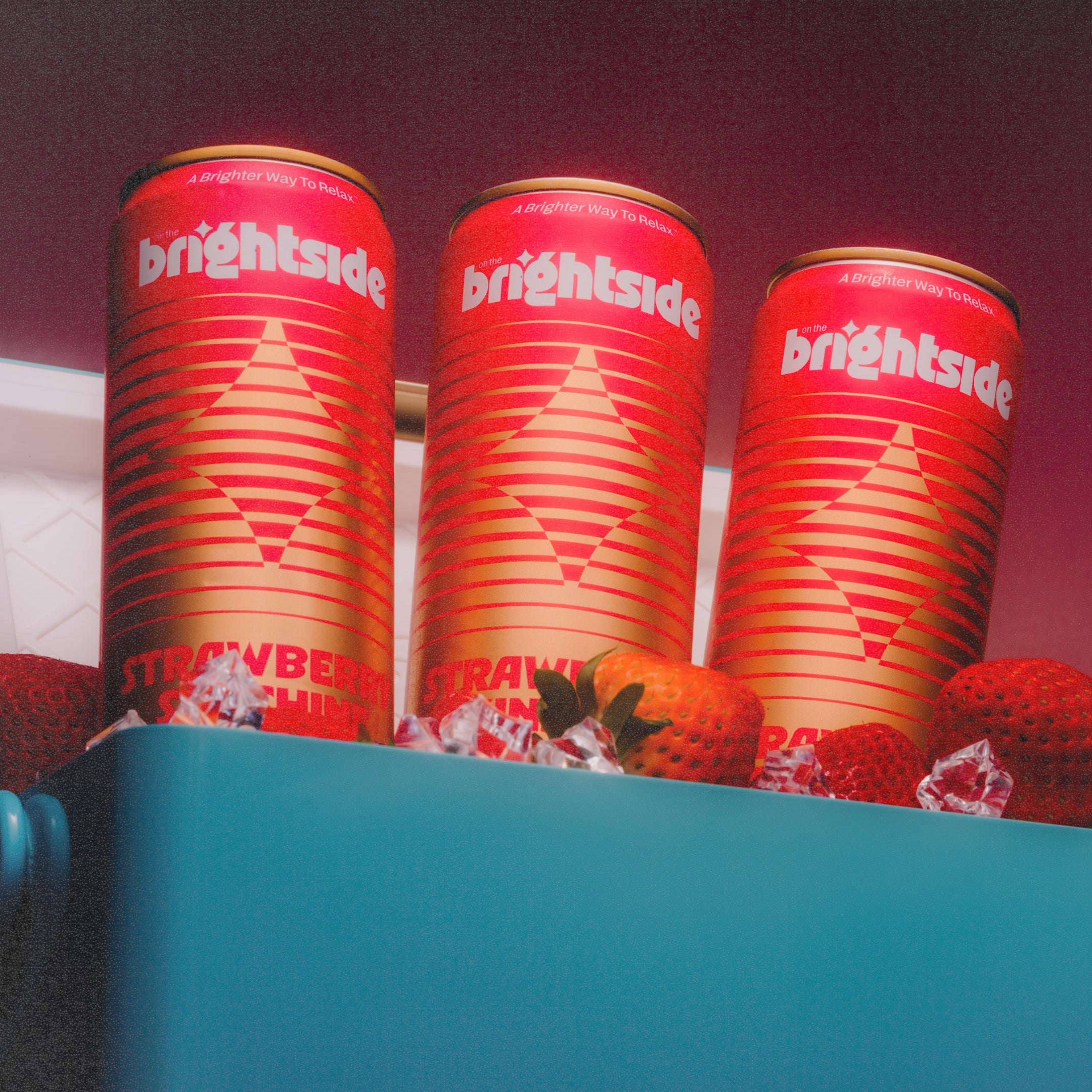 Three on the Brightside strawberry sunshine cans with strawberries inside a blue cooler