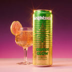 Can of On the Brightside Guava Glow soda with a glass of sparkling drink and guava slice on a purple background