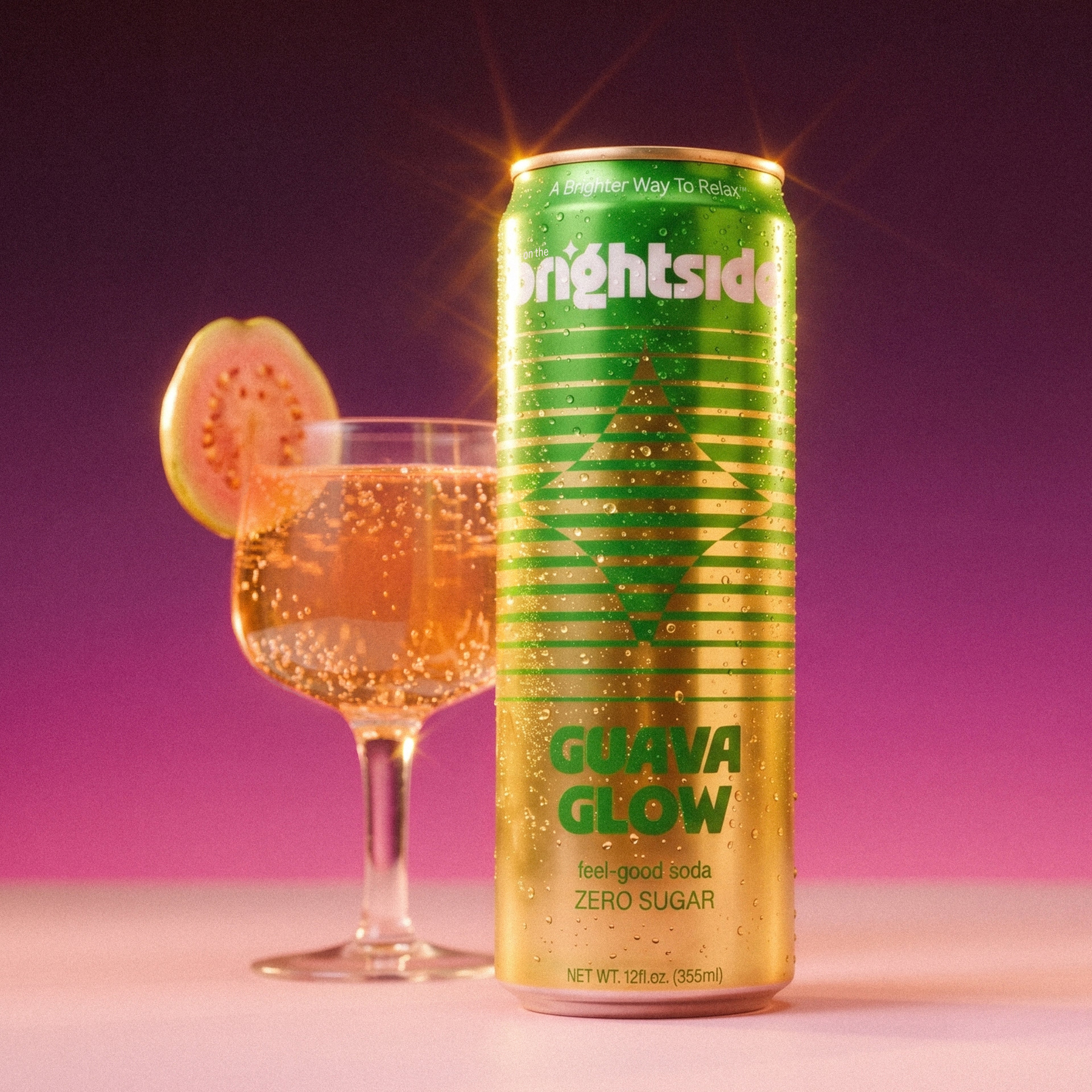 Can of On the Brightside Guava Glow soda with a glass of sparkling drink and guava slice on a purple background