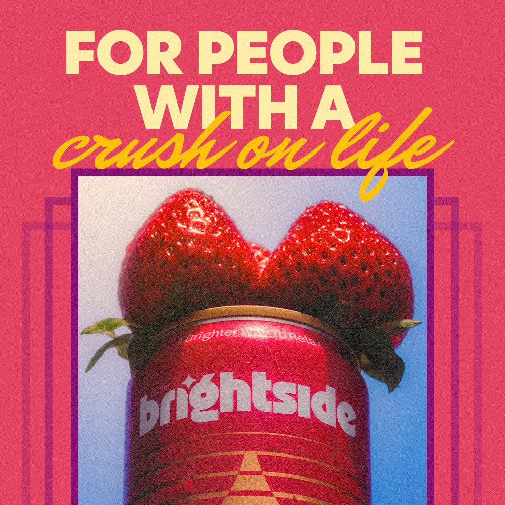 A graphic design with the text 'FOR PEOPLE WITH A crush on life' in cream and yellow lettering over a photo of two fresh strawberries on top of a strawberry sunshine Brightside can, set against a pink background with purple geometric accents.