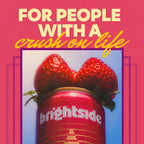 A graphic design with the text 'FOR PEOPLE WITH A crush on life' in cream and yellow lettering over a photo of two fresh strawberries on top of a strawberry sunshine Brightside can, set against a pink background with purple geometric accents.