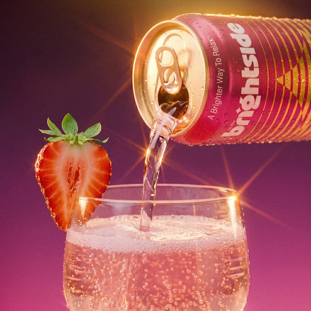 A can of Brightside sparkling drink tilted to pour into a clear glass, with a sliced strawberry garnish on the rim, against a purple gradient background with bright light effects.