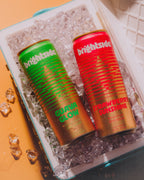 Two cans of On the Brightside drinks, one strawberry sunshine, one Guava Glow, on top of ice inside a cooler.
