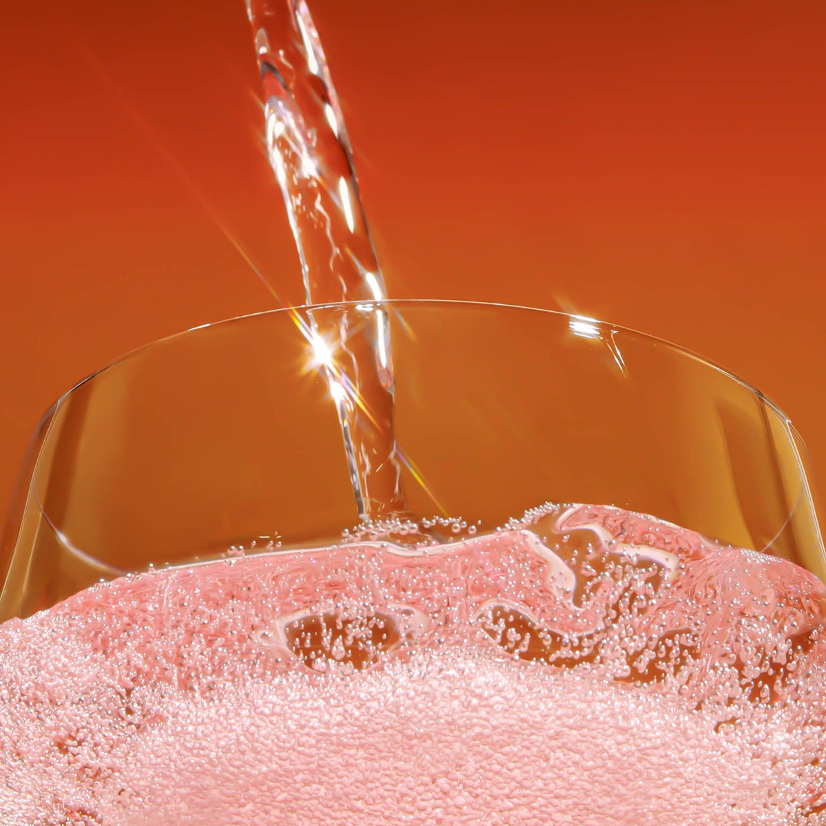 brightside strawberry sunshine being poured into a clear glass against a warm orange gradient background.
