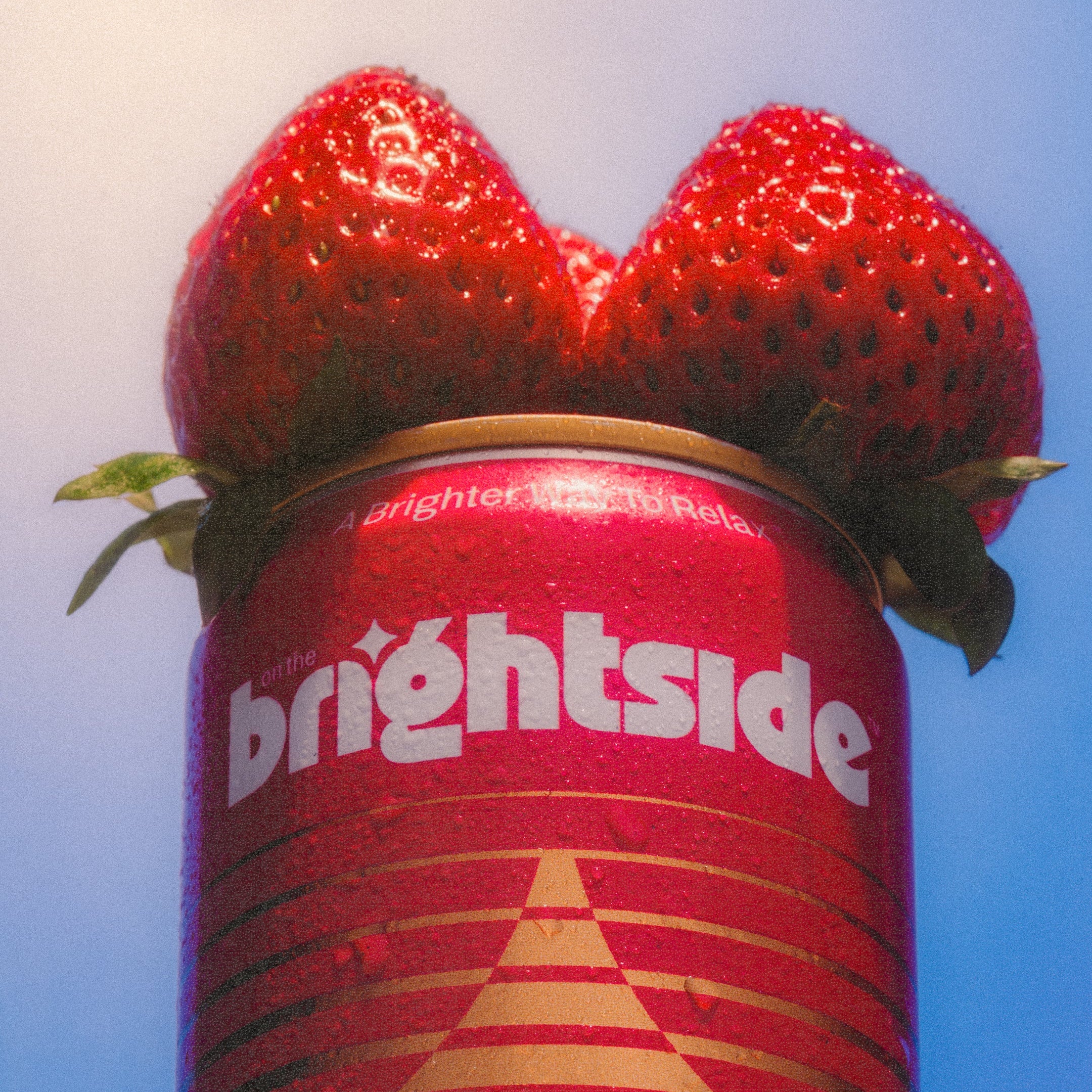 Strawberry Sunshine On the Brightside beverage topped with two fresh red strawberries against a pale blue background.