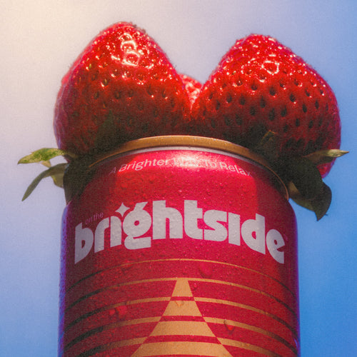 Strawberry Sunshine On the Brightside beverage topped with two fresh red strawberries against a pale blue background.